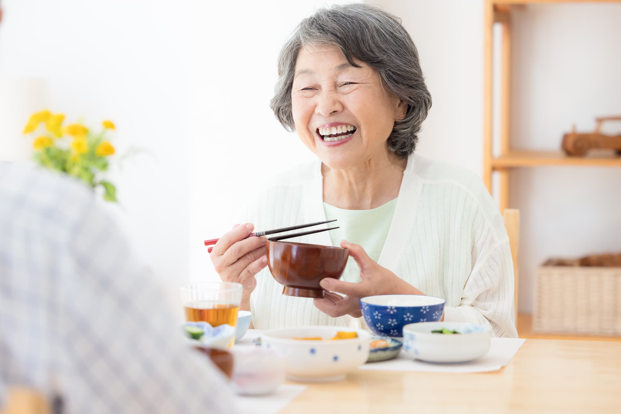 目立たない入れ歯のノンクラスプデンチャーを装着し笑顔で食事をする女性