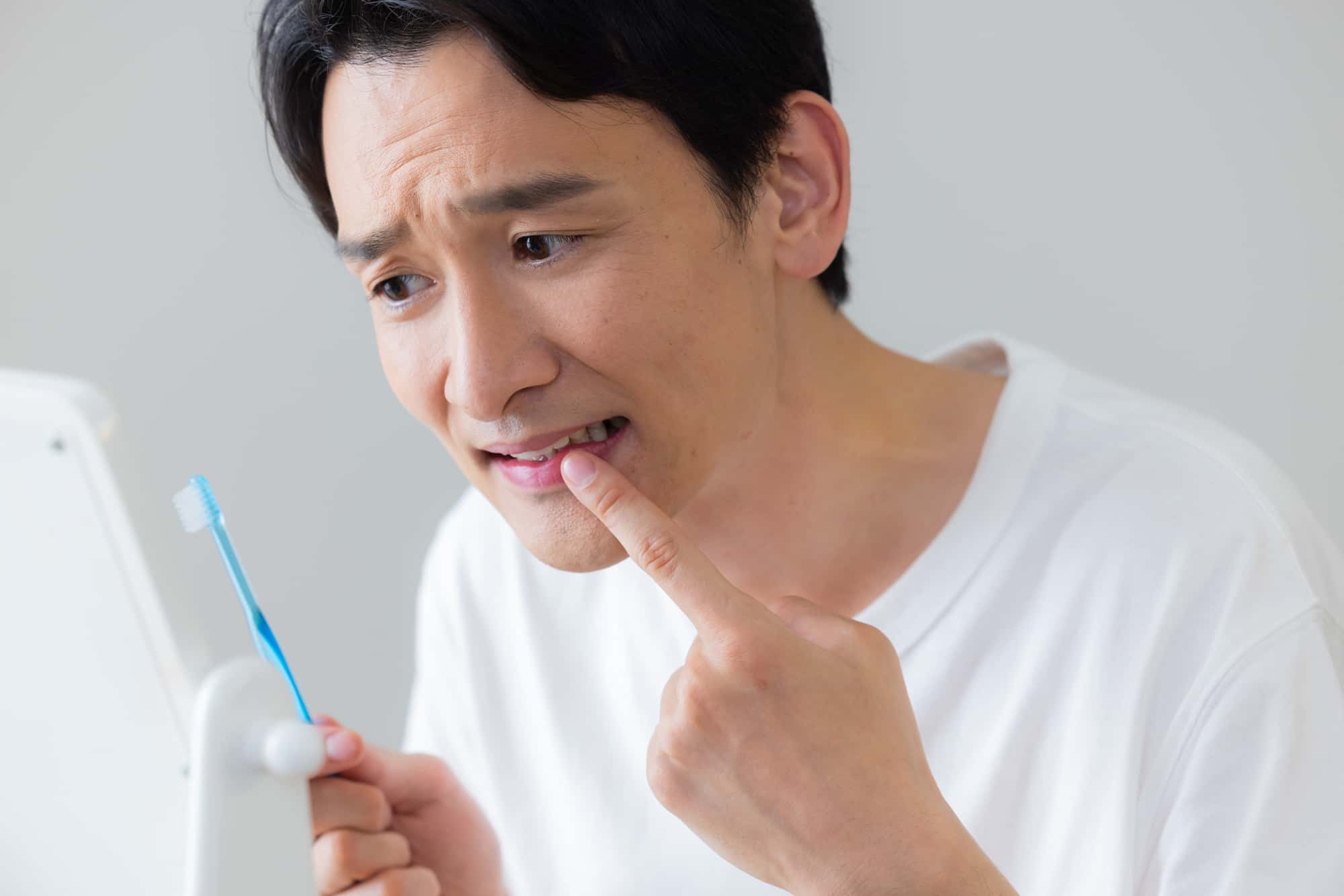 ぐらつく歯を指で触る男性