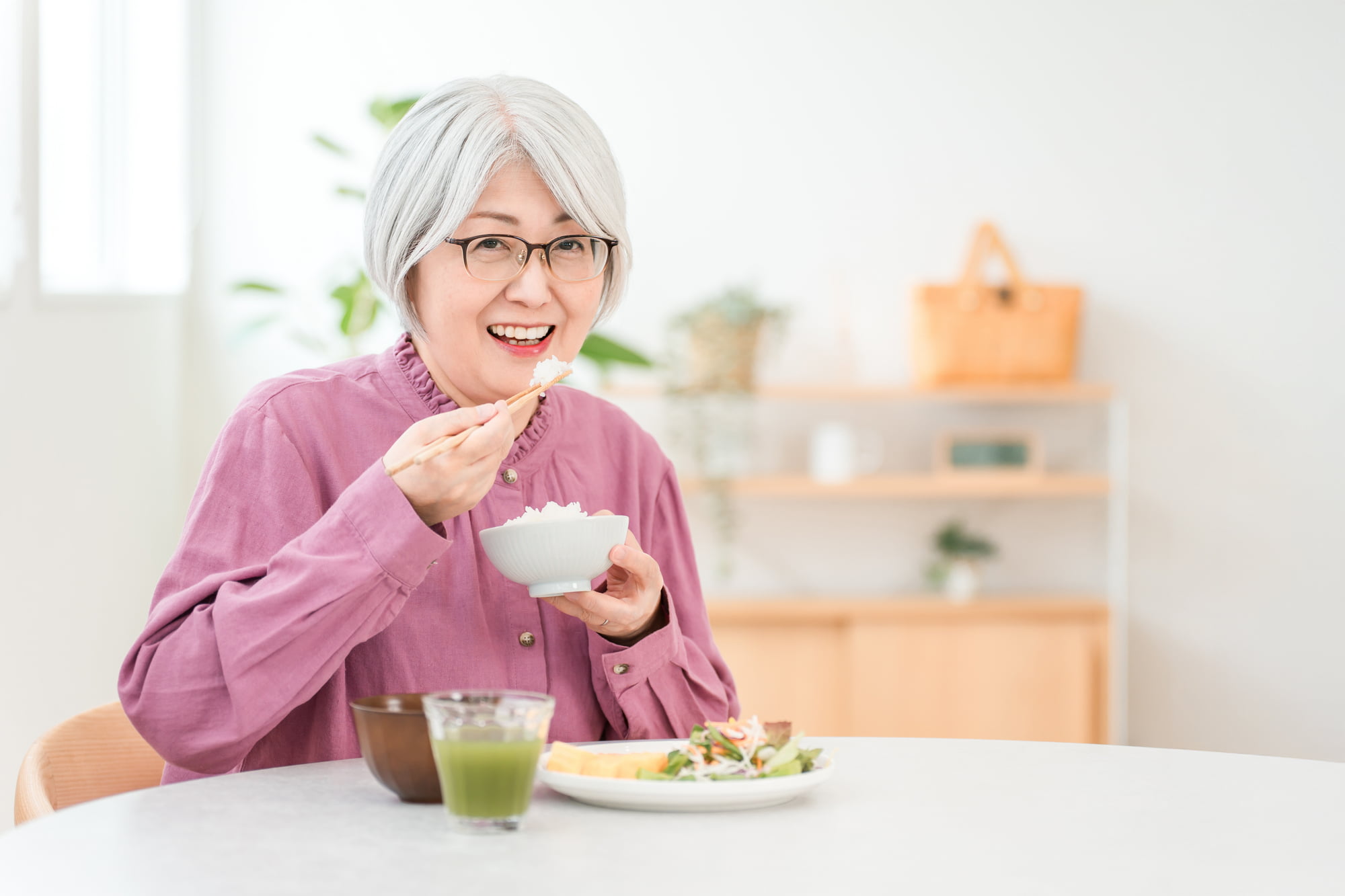 自分に合った入れ歯で快適に食事をする女性
