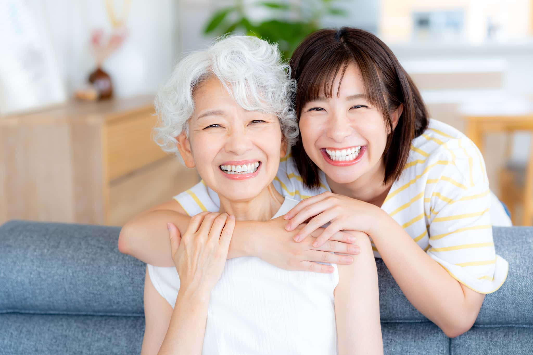 全部の歯をインプラントにして満足している祖母に喜んで抱きついている笑顔の孫