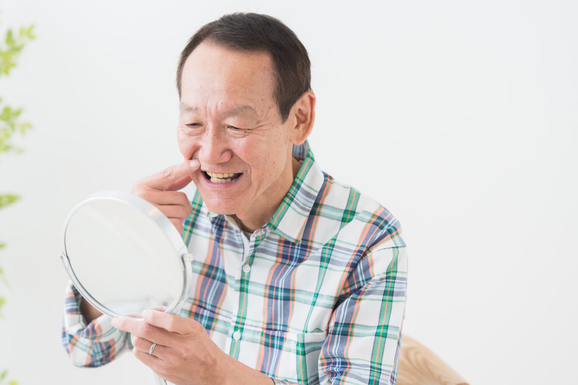 目立つ前歯の入れ歯が気になって鏡を見る男性